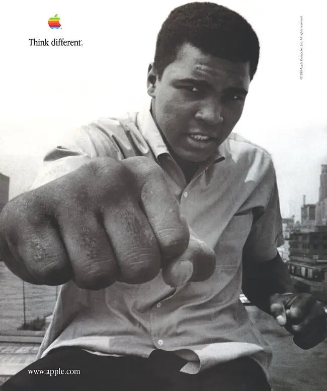 Apple Think Different poster featuring Muhammad Ali extending a fist toward the camera beneath the rainbow Apple logo.