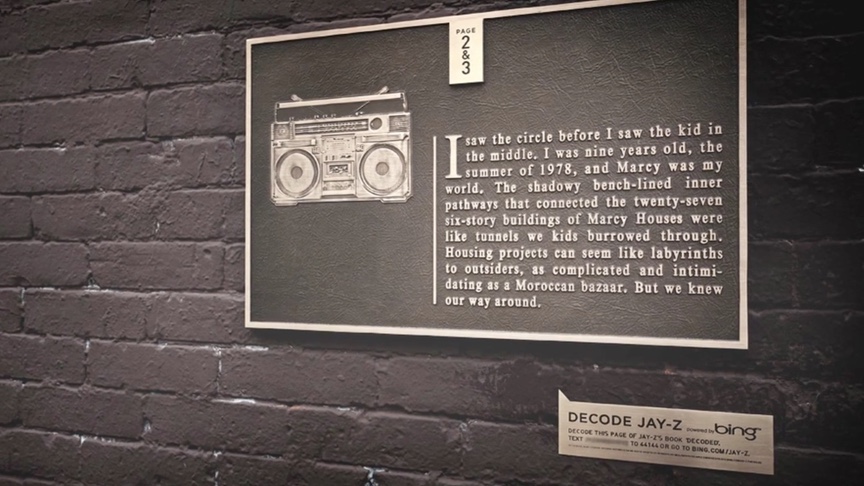 A Decoded memoir page cast as a bronze plaque on a brick wall at Marcy Houses