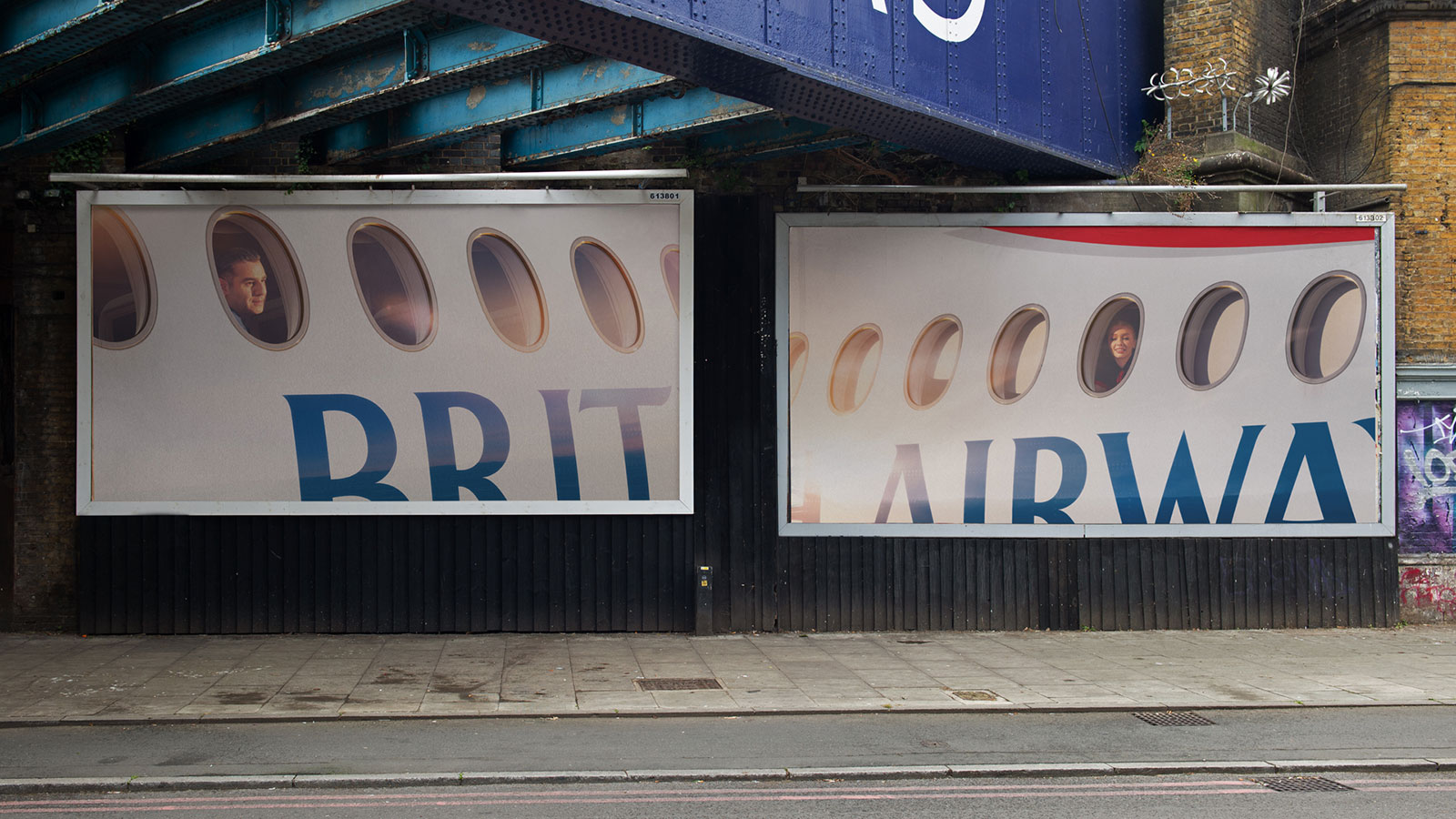 Two British Airways Windows posters installed side by side beneath a railway bridge, each isolating a passenger within a row of aircraft windows.