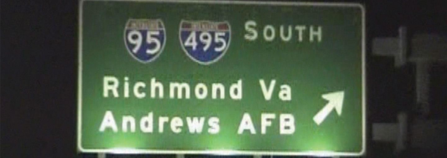 Night driving footage passes a highway sign pointing toward Andrews Air Force Base.