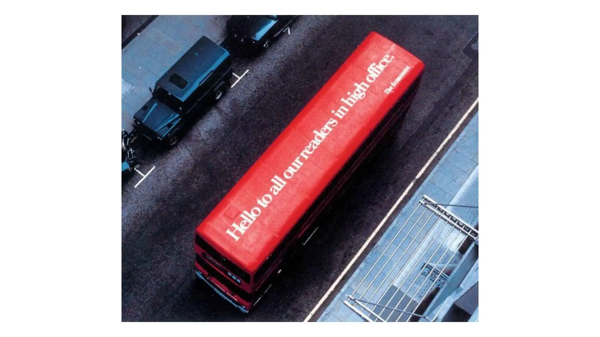 A red London bus seen from above with the line ‘Hello to all our readers in high office’ printed across its roof.
