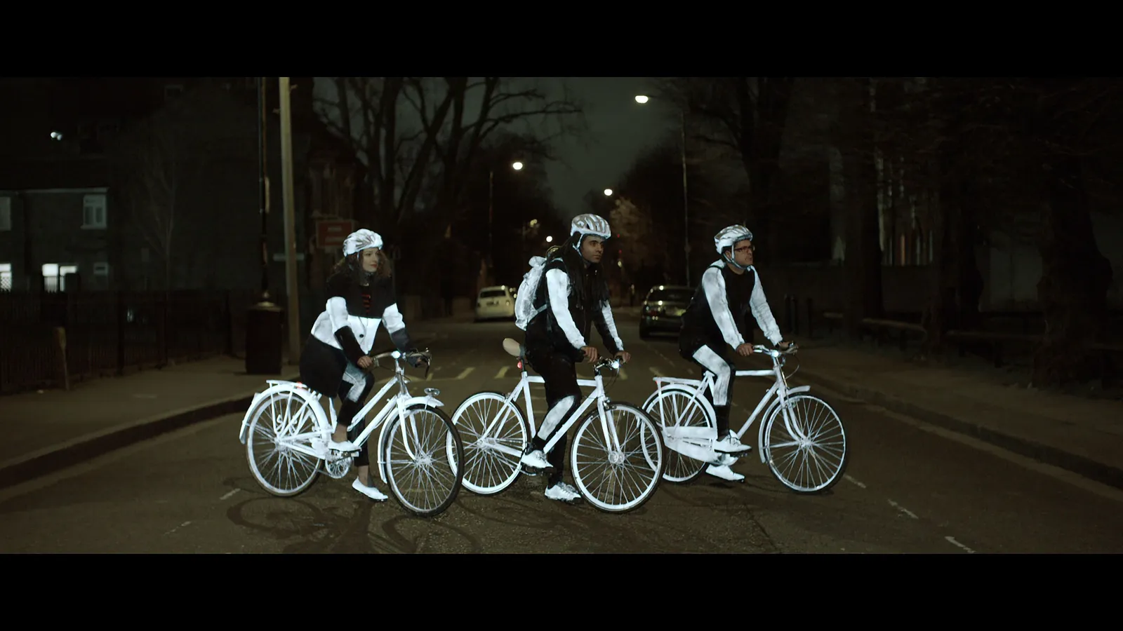 Cyclists wearing LifePaint-treated clothing glowing brightly on a dark street