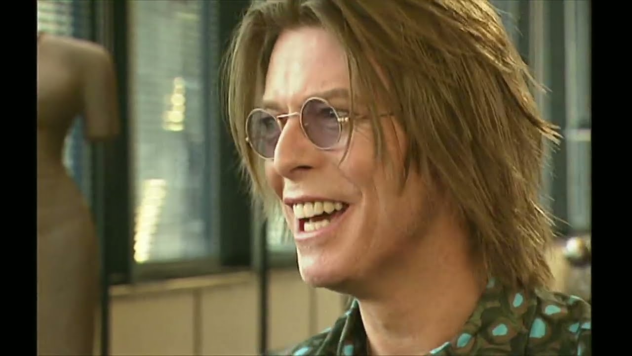 David Bowie smiling in round glasses during his BBC Newsnight interview with Jeremy Paxman.