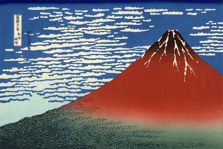 Hokusai woodblock print of red Mount Fuji beneath a blue sky patterned with clouds